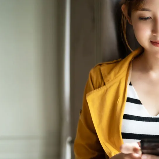 Person, smiling looking at a mobile phone