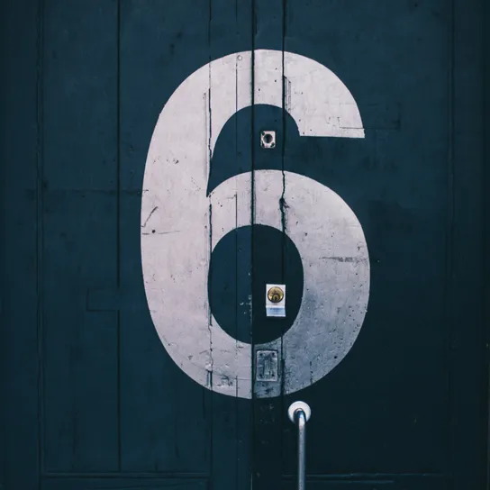 The number 6 painted in white on a dark door with industrial handle