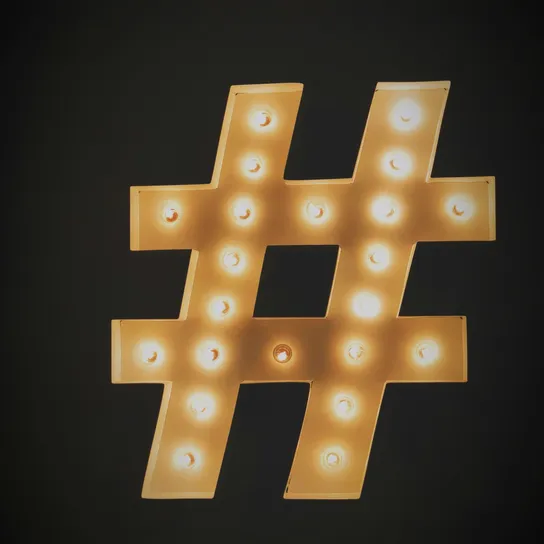 Hashtag sign made of lights glowing against a black background