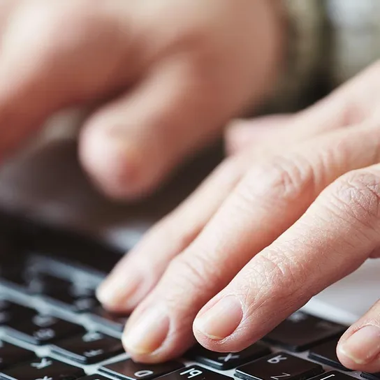 Close up of two hands typing on a keyboard