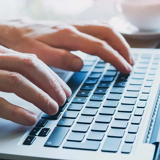 Two hands typing on a laptop